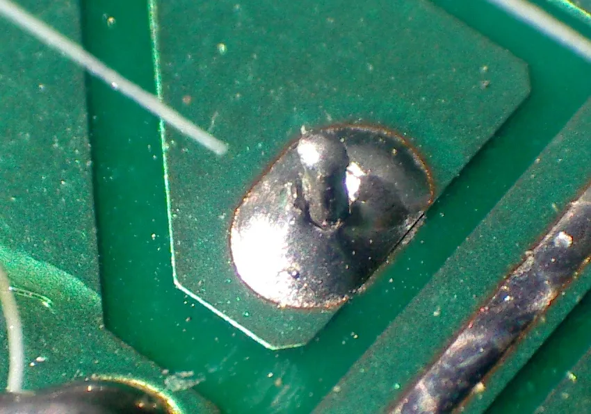 A dull, grainy cold solder joint on a circuit board